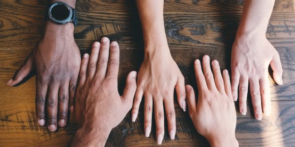 five human hands on brown surface